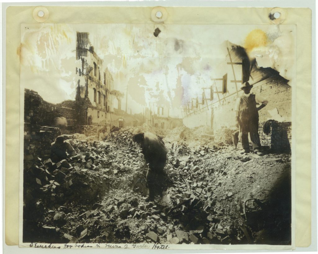 men in overalls sifting through building rubble w/shovels
