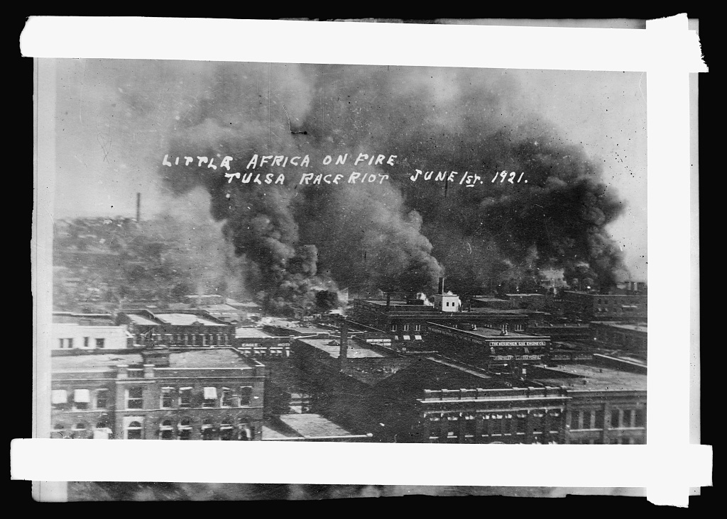aerial view of city w/thick dark smoke clouds coming from buildings