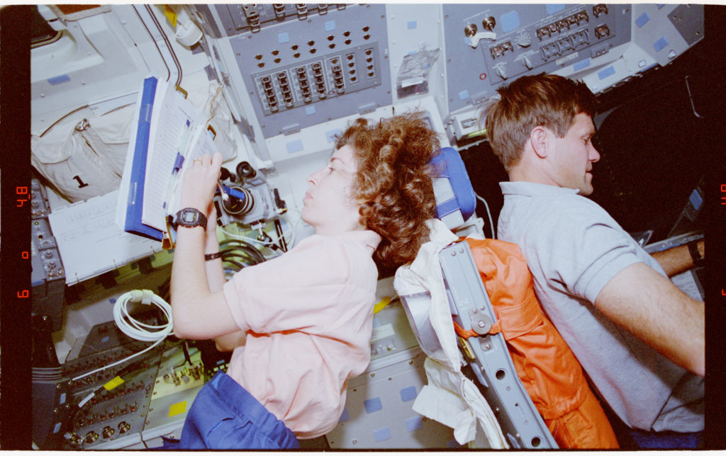 Ochoa and another astronaut are back to back writing info in books