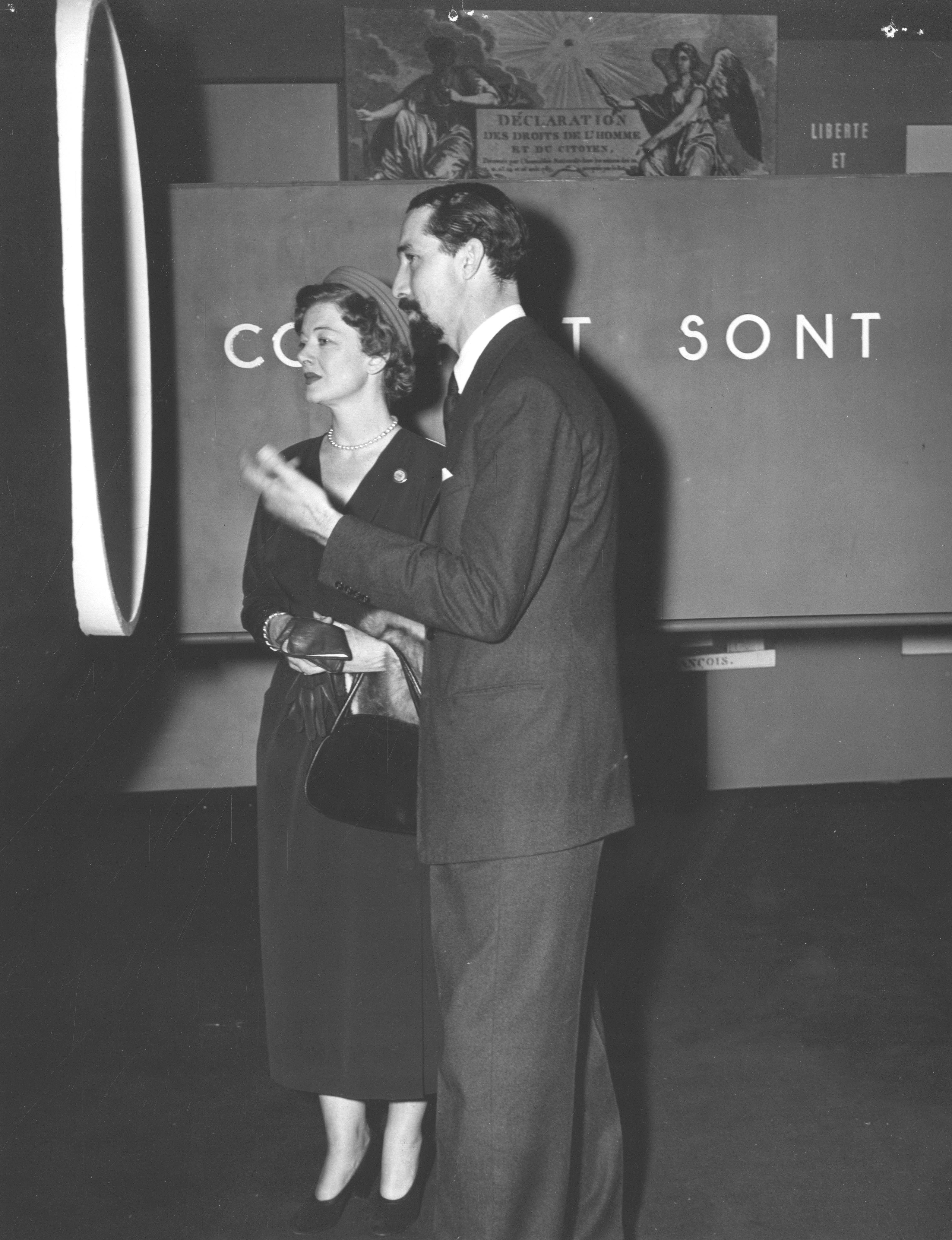 This is a photograph of Miss Myrna Loy, American film star in Paris for the conferences is being shown the Exhibit of Human Rights by Clive Entwistle.