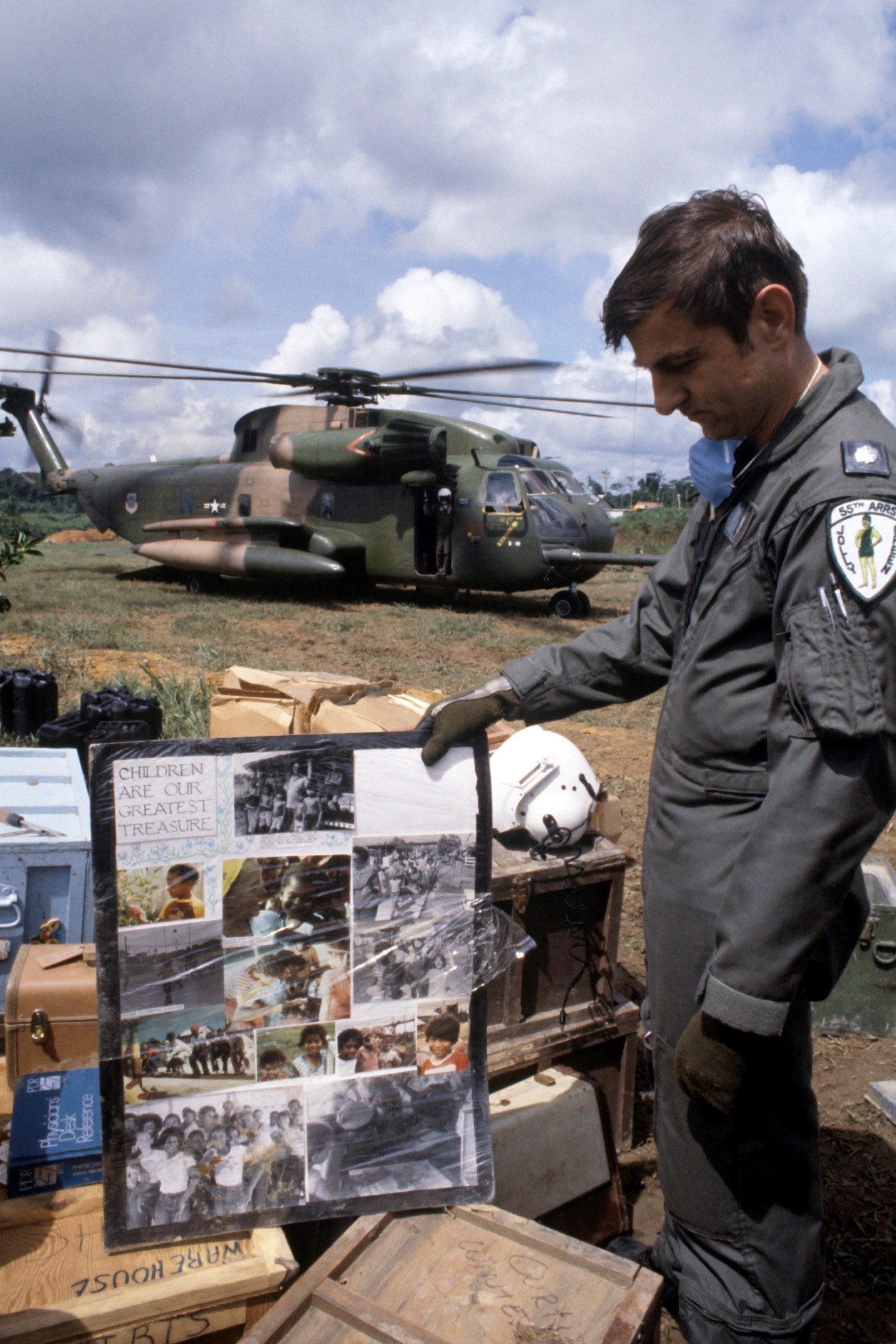 Image of Lieutenant Colonel (LTC) Leonard Morrisey, an HH-53 Jolly Green Giant helicopter pilot from the 55th Aerospace Rescue and Recovery Squadron, examines a poster found at the compound as the remains of the victims of the Jonestown tragedy are loaded aboard the helicopter (NAID 6413446)