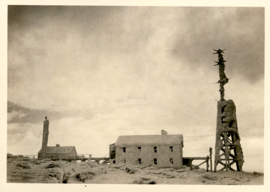 Image of radio tower and adjacent buildings covered with snow.