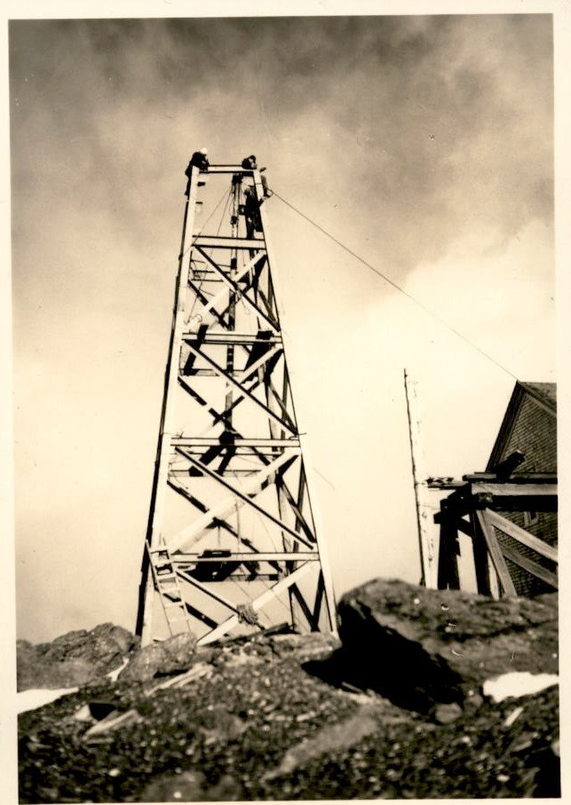 Image of a tall antenna tower with workers on top of it.