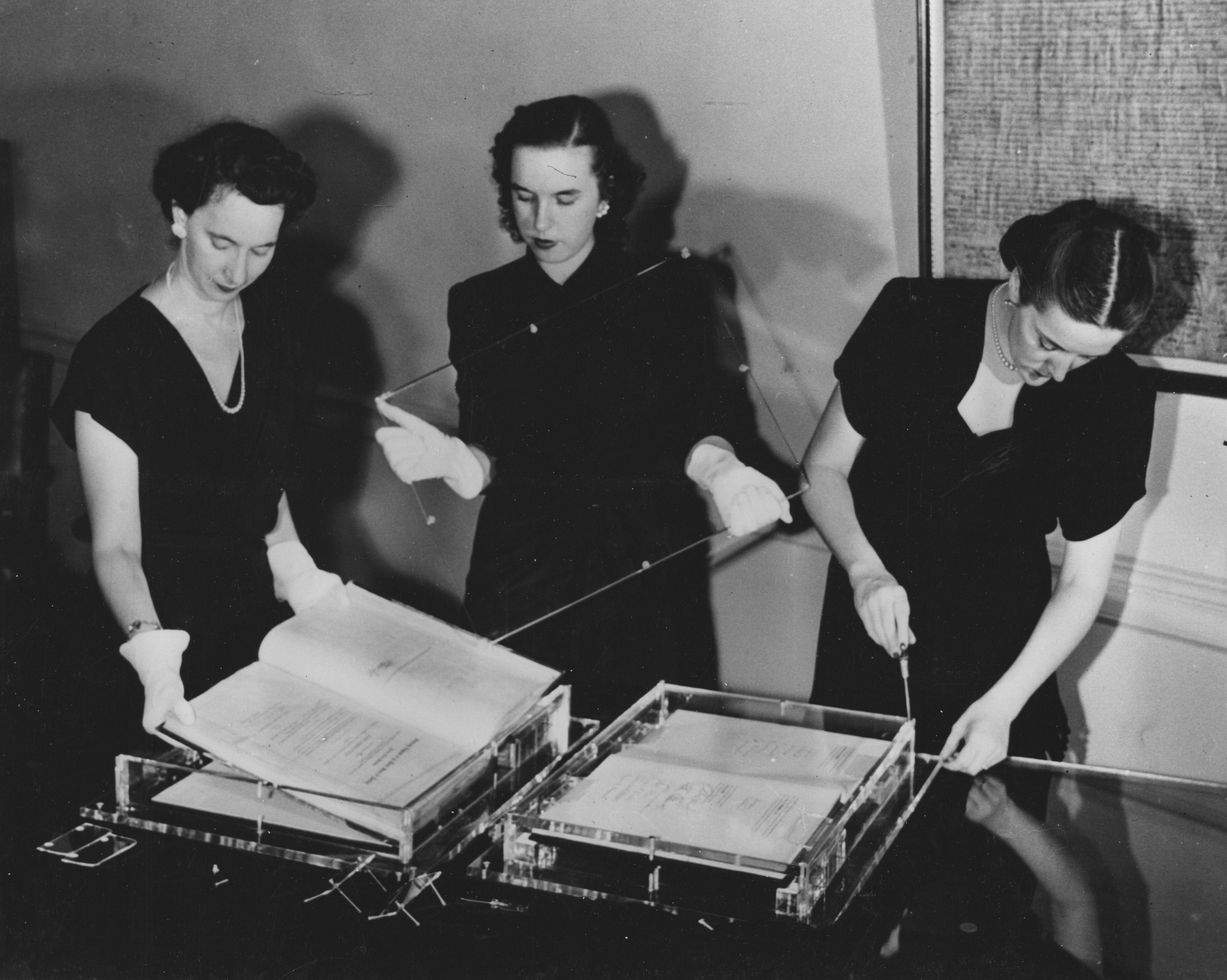 Three women working on exhibit cases.